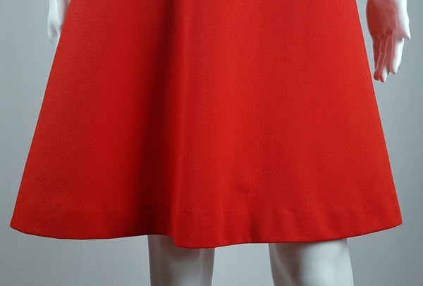 Close up back hemline view of a vintage 1970s Kenny Classics Donnkenny orange-red mod dress with a white collar, navy and white waist bands displayed on a mannequin
