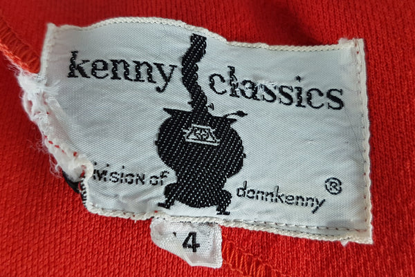 Label closeup view of a vintage 1970s Kenny Classics Donnkenny orange-red mod dress with a white pointed collar, navy and white waist bands and contrasting covered buttons displayed on a mannequin
