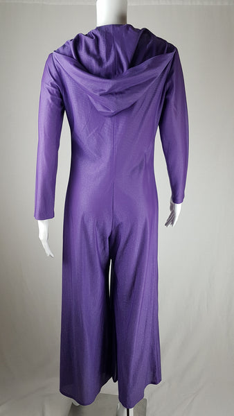 Back view of a 1970s Nu-Mode purple jumpsuit with a draped hood, V-neckline, front zip and ties, long sleeves and wide legs displayed on a mannequin 