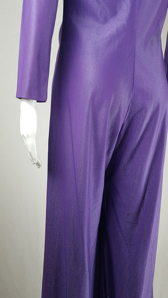 Back waistline view of a 1970s Nu-Mode purple jumpsuit with a draped hood, V-neckline, front zip and ties, long sleeves and wide legs displayed on a mannequin 