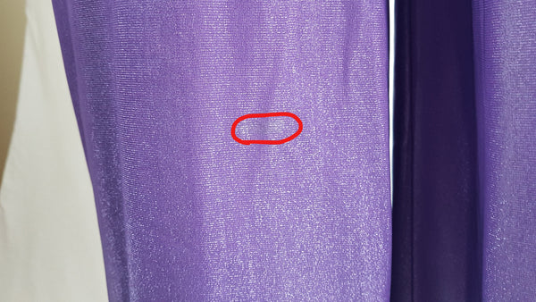 Flaw circled in red of a 1970s Nu-Mode purple jumpsuit with a draped hood, V-neckline, front zip and ties, long sleeves and wide legs displayed on a mannequin 