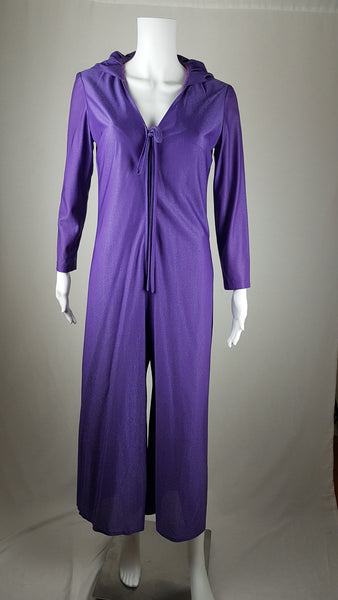 Front view of a 1970s Nu-Mode purple jumpsuit with a draped hood, V-neckline, front zip and ties, long sleeves and wide legs displayed on a mannequin 