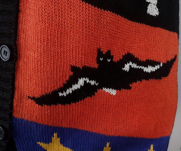 Close-up of the black intarsia-knit bat with white embroidered details against an orange panel