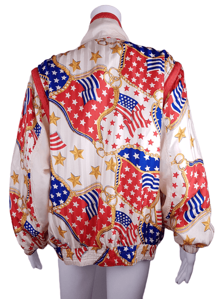 Full back view of a Vintage 1980s - 1990s  Mureli silk bomber jacket with a red, white, blue and gold USA flag and chain print, detachable sleeves, red trim and an oversized blouson silhouette, displayed on a mannequin