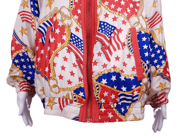 Closeup view elasticated waist hem of a Vintage 1980s - 1990s  Mureli silk bomber jacket with a red, white, blue and gold USA flag and chain print, detachable sleeves, red trim and an oversized blouson silhouette, displayed on a mannequin