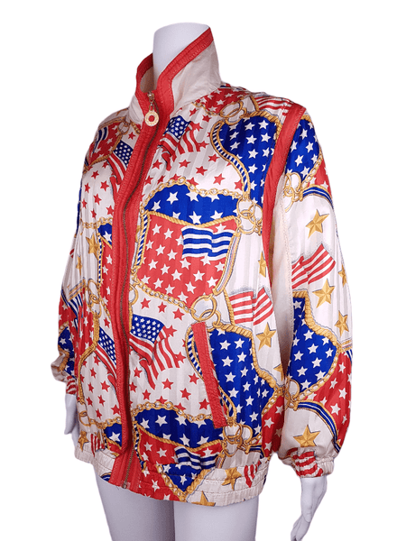 Full three quarter view of a Vintage 1980s - 1990s  Mureli silk bomber jacket with a red, white, blue and gold USA flag and chain print, detachable sleeves, red trim and an oversized blouson silhouette, displayed on a mannequin