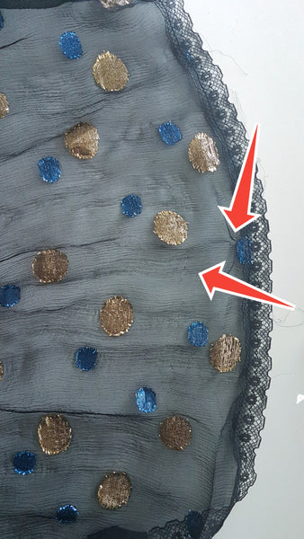 Condition photograph with red arrows identifying tiny pinholes near the lace-trimmed hem of the Vintage 1980s Edith Strauss Black Silk Metallic Polka-Dot Midi Dress