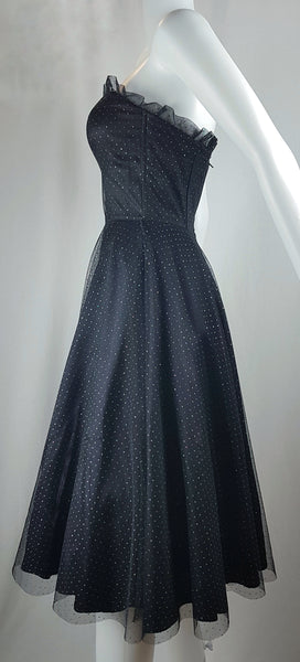 Full side view of a vintage 1980's Gunne Sax black formal dress with multicolor glitter dots, a pleated tulle sweetheart neckline and fitted bodice and full sweep skirt with a built-in crinoline displayed on a mannequin