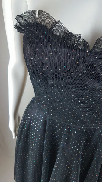 Closeup front bodice and waistline view of a vintage 1980's Gunne Sax black formal dress with multicolor glitter dots, a pleated tulle sweetheart neckline and fitted bodice and full sweep skirt with a built-in crinoline displayed on a mannequin
