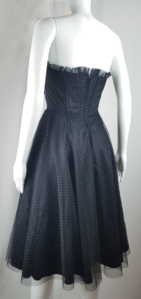 Full three quarter view of a vintage 1980's Gunne Sax black formal dress with multicolor glitter dots, a pleated tulle sweetheart neckline and fitted bodice and full sweep skirt with a built-in crinoline displayed on a mannequin