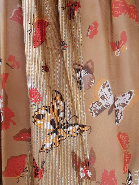 Detailed view of the sheer gold silk woven with metallic threads and printed with butterflies, moths, insects and botanical motifs.