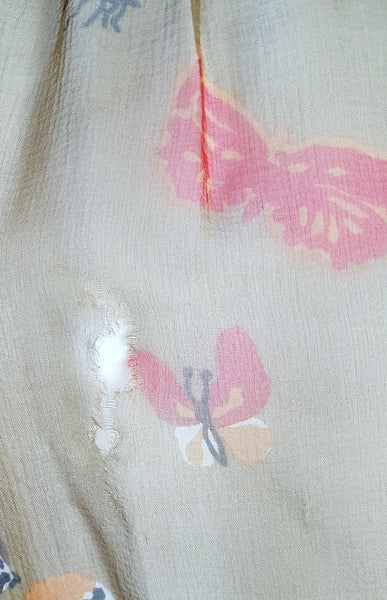 Condition close-up showing an approximately half-inch hole and nearby fabric separation in the silk near the kaftan’s shoulder.