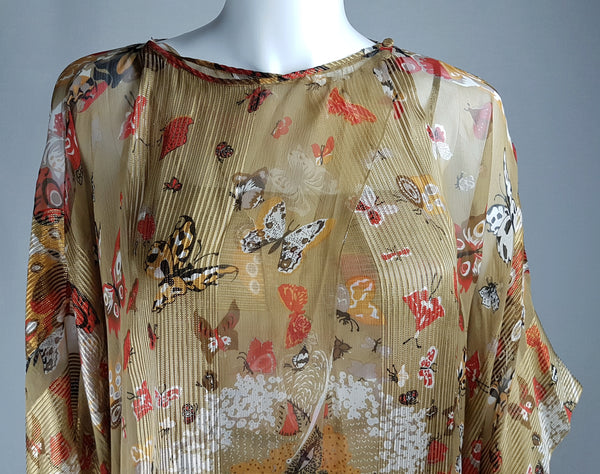 Close-up of the vintage 1980s Soo Yung Lee silk kaftan’s boat neckline, left-shoulder button and butterfly-and-insect print on gold metallic silk.