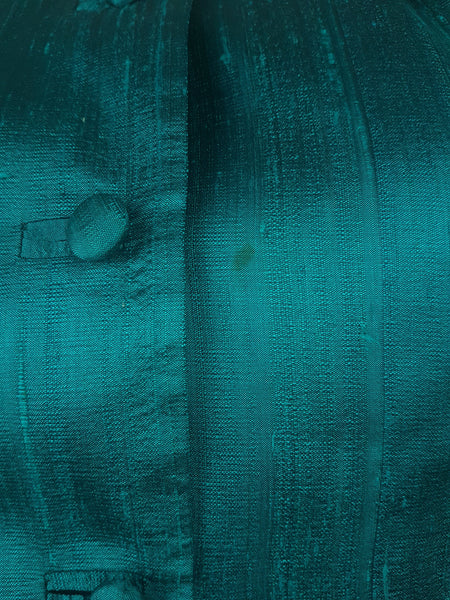 Condition close-up showing a faint residual mark near the front button placket and the natural slubbed texture of the teal silk.