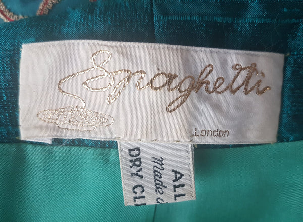 Close-up of the metallic-script Spaghetti London label and attached dry-clean care tag inside the teal silk jacket.