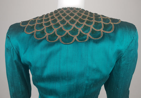 Back close-up of the broad collar embellished with layered scallops, metallic-gold braid, fine red cord and emerald-green beads.