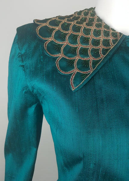 Close-up of the broad collar embellished with layered scallops, metallic-gold braid, fine red cord and emerald-green beads.