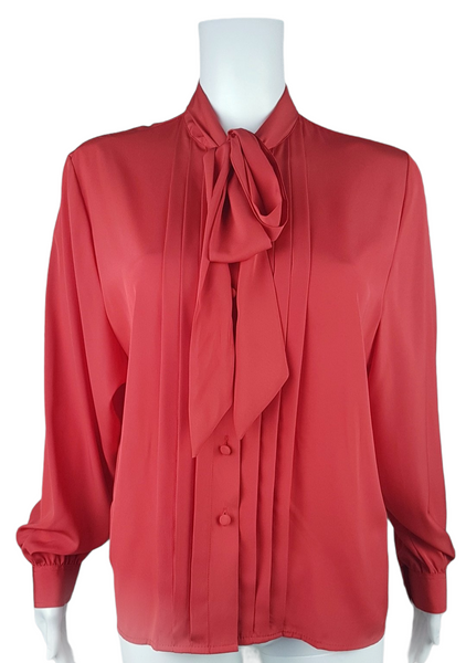 Front view of a vintage 1980s St Michael red pussy-bow blouse with stitched front pleats, fabric-covered buttons and gathered long sleeves displayed on a mannequin 