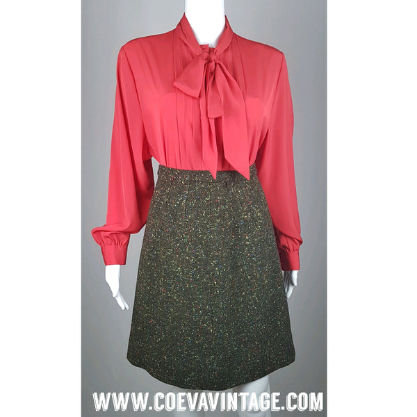 Front view of a vintage 1980s St Michael red pussy-bow blouse with stitched front pleats, fabric-covered buttons and gathered long sleeves displayed on a mannequin with a Green Confetti Bouclé A-Line Skirt 