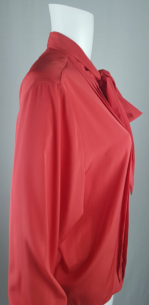Side view of a vintage 1980s St Michael red pussy-bow blouse with stitched front pleats, fabric-covered buttons and gathered long sleeves displayed on a mannequin 