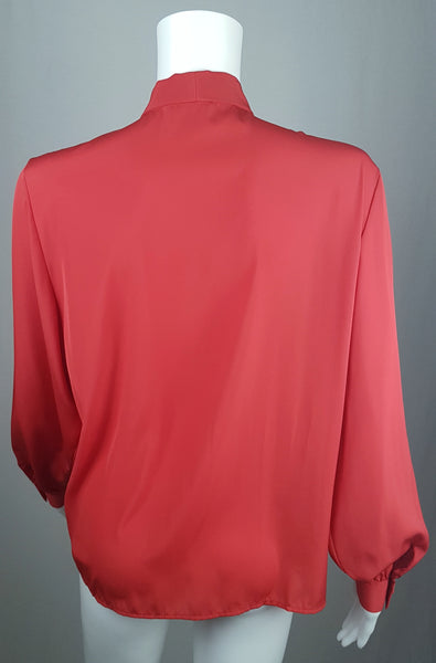 Back view of a vintage 1980s St Michael red pussy-bow blouse with stitched front pleats, fabric-covered buttons and gathered long sleeves displayed on a mannequin 