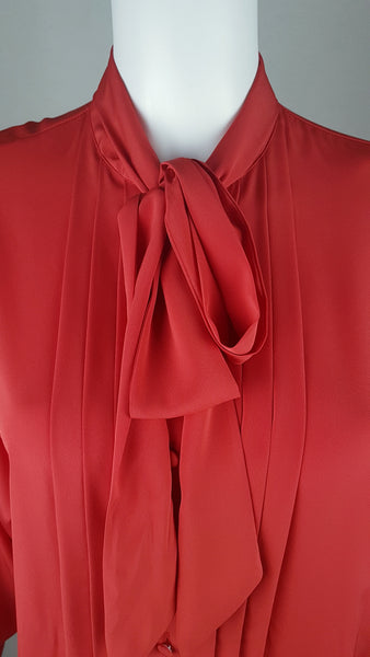 Closeup view of tied pussybow on a vintage 1980s St Michael red pussy-bow blouse with stitched front pleats, fabric-covered buttons and gathered long sleeves displayed on a mannequin 