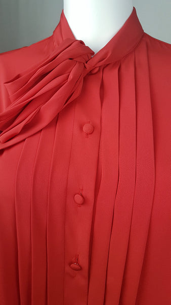 Closeup view of buttons on a vintage 1980s St Michael red pussy-bow blouse with stitched front pleats, fabric-covered buttons and gathered long sleeves displayed on a mannequin 