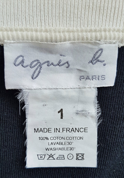 Close-up of the Agnès b. Paris label and care tag inside a vintage 1990s black-and-white cotton cardigan top, showing size 1 and Made in France.