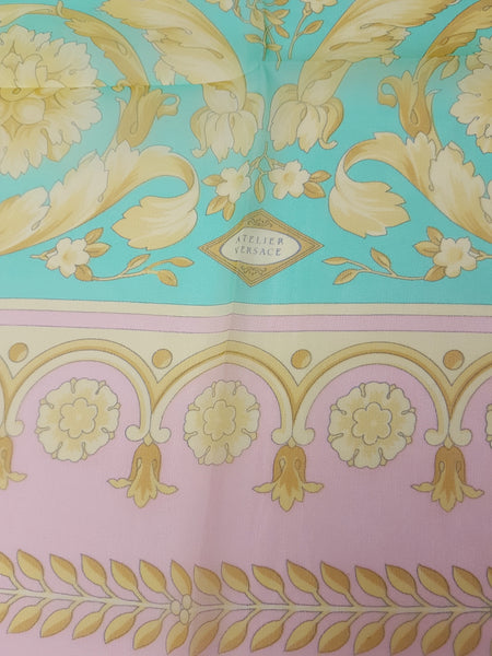 Fabric closeup of Vintage Atelier Versace silk scarf, showing its aqua centre, pink border and ornate floral design.