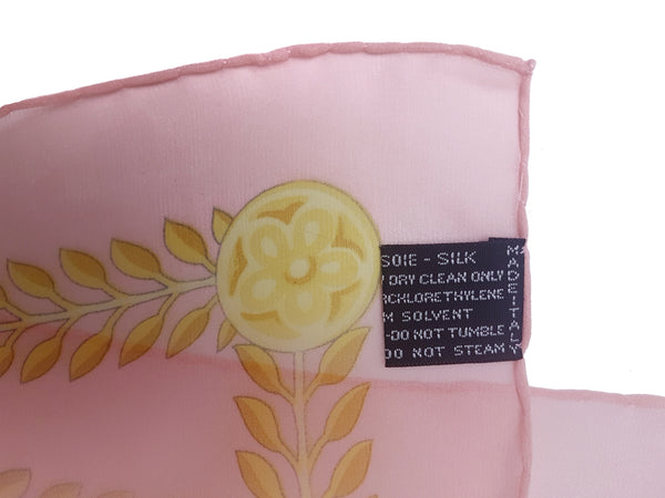 Care and material label of a vintage early 1990s Atelier Versace square silk scarf in pastel pink and aqua with ornate gold floral scrollwork.