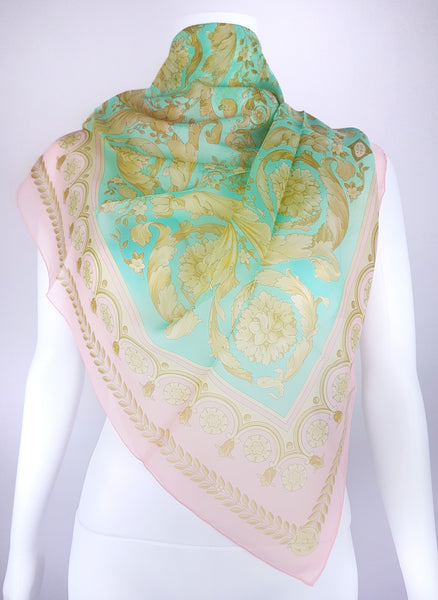 Vintage 1990s Atelier Versace silk scarf styled around a dress form, showing its aqua centre, pink border and ornate floral design.