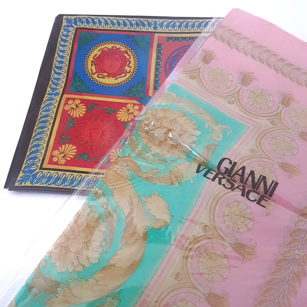 Deadstock 1990s Atelier Versace pastel pink and aqua silk scarf preserved in its original clear sleeve and presentation packaging.
