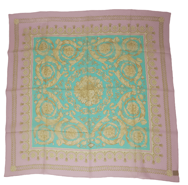 Flatlay full view of a vintage early 1990s Atelier Versace square silk scarf in pastel pink and aqua with ornate gold floral scrollwork.