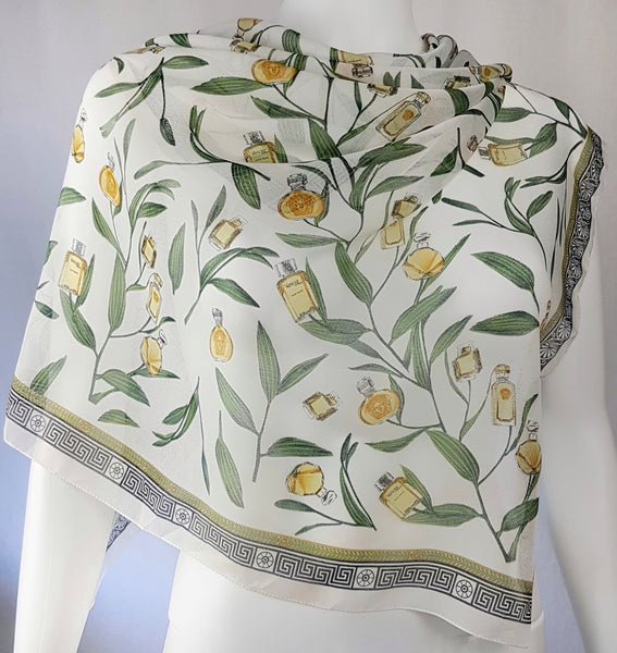 Large vintage 1990s Gianni Versace Profumi square scarf spread across a dress form, with green branches, gold perfume bottles and a black border.