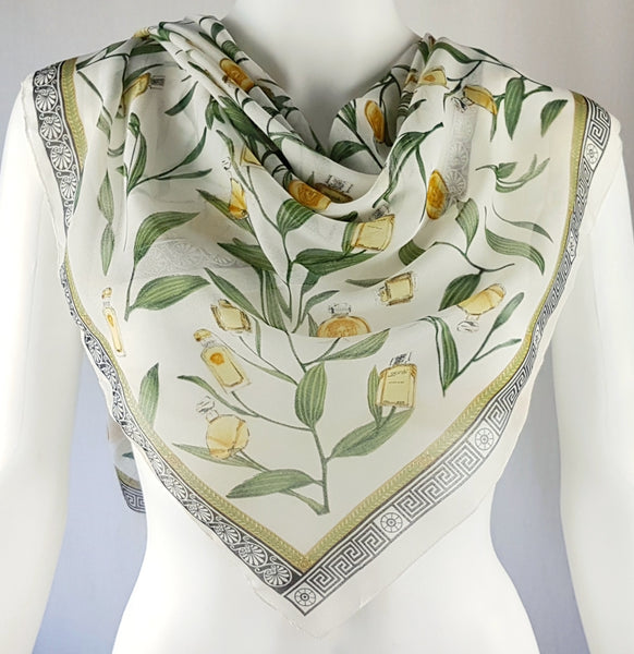 Vintage 1990s Gianni Versace Profumi ivory chiffon scarf draped in a triangle, showing its perfume-bottle print and Greek-key border.