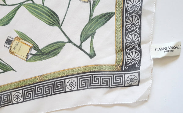 Close-up of the black Greek-key border and green-and-gold botanical band on a vintage 1990s Gianni Versace Profumi ivory chiffon scarf.