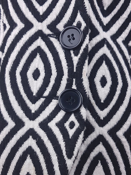 Close-up of the black button fastening on a vintage 1990s Le Château black-and-white patterned jacket.