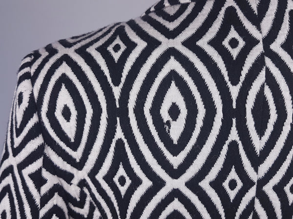 Back view of one small damaged area on the left rear shoulder on  vintage 1990s Le Château black-and-white patterned jacket.The disruption is not immediately noticeable within the bold pattern but should be considered before purchase.