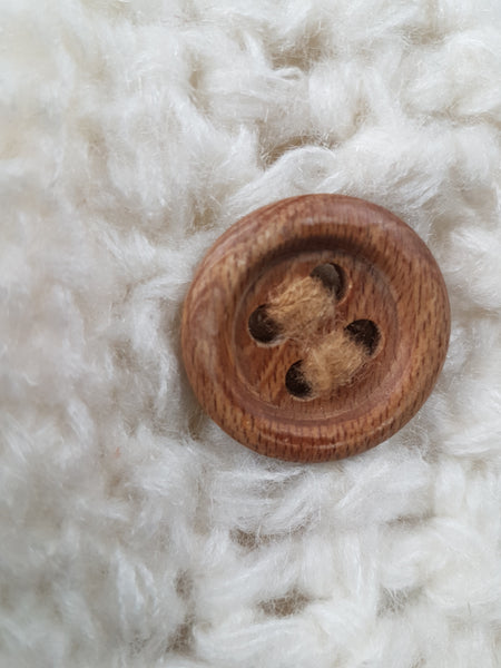 Closeup image of a wooden button on a vintage 1990's Leroy Knitwear cream cardigan sweater with deer motifs and wooden buttons, displayed on a mannequin.