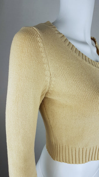 Three-quarter front view of a vintage 2000s sand-beige Betsey Johnson cropped cardigan with three-quarter sleeves, pearl-effect buttons and a cropped ribbed hem displayed on a mannequin