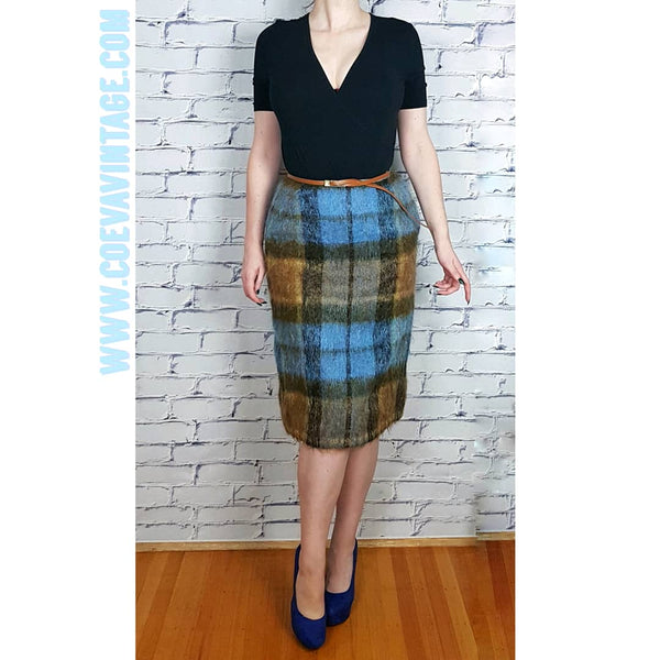 Woman wearing a black v-neck short sleeve top, and a Vintage 1970s Andrew Stewart mohair and wool pencil skirt with a fuzzy plaid pattern in blue, brown, grey, and olive 