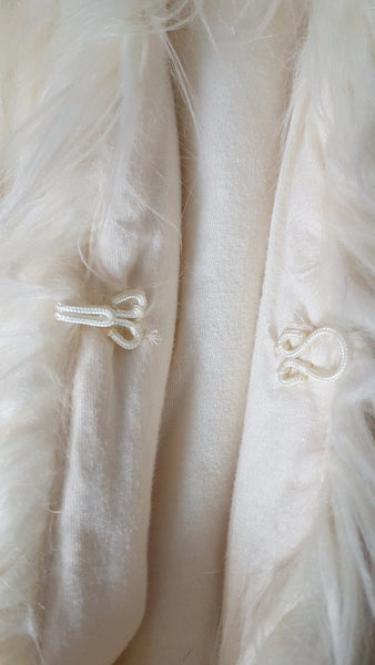 Close-up view of the decorative ivory braided fastening and smooth cream lining on a vintage-inspired faux-fur vest.