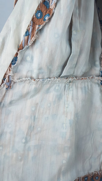 inner fabric and construction detail view of a vintage late 1950s dressmaker-made Vogue Couturier Design tunic top in a tan and blue abstract floral print, with circular cape sleeves and a fitted waist displayed on a mannequin 