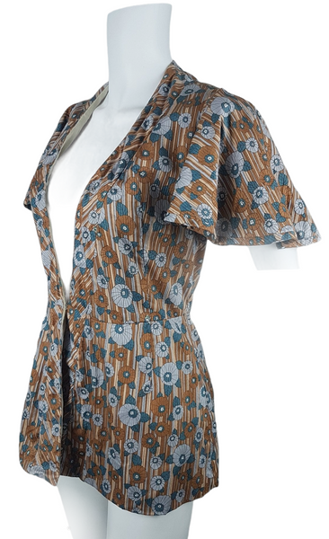 three quarter view of a vintage late 1950s dressmaker-made Vogue Couturier Design tunic top in a tan and blue abstract floral print, with circular cape sleeves and a fitted waist displayed on a mannequin 