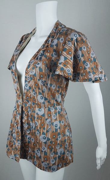 three quarter view of a vintage late 1950s dressmaker-made Vogue Couturier Design tunic top in a tan and blue abstract floral print, with circular cape sleeves and a fitted waist displayed on a mannequin 