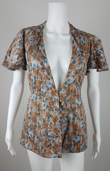 front view of a vintage late 1950s dressmaker-made Vogue Couturier Design tunic top in a tan and blue abstract floral print, with circular cape sleeves and a fitted waist displayed on a mannequin 