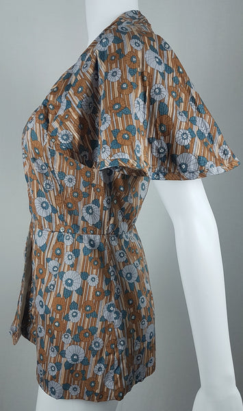 side view of a vintage late 1950s dressmaker-made Vogue Couturier Design tunic top in a tan and blue abstract floral print, with circular cape sleeves and a fitted waist displayed on a mannequin 