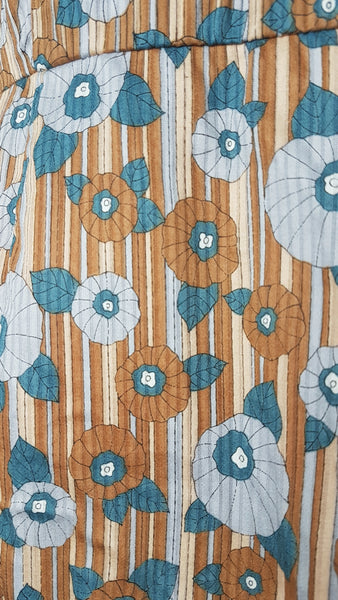 print and fabric detail view of a vintage late 1950s dressmaker-made Vogue Couturier Design tunic top in a tan and blue abstract floral print, with circular cape sleeves and a fitted waist displayed on a mannequin 