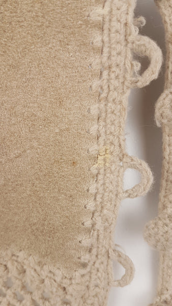 Condition close-up showing a small pale worn area along the crochet-edged front beside the loop fastenings.