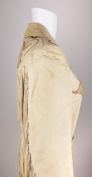 Side view of a sand-beige leather Western jacket showing its fitted waist, curved yoke and fringed sleeve.